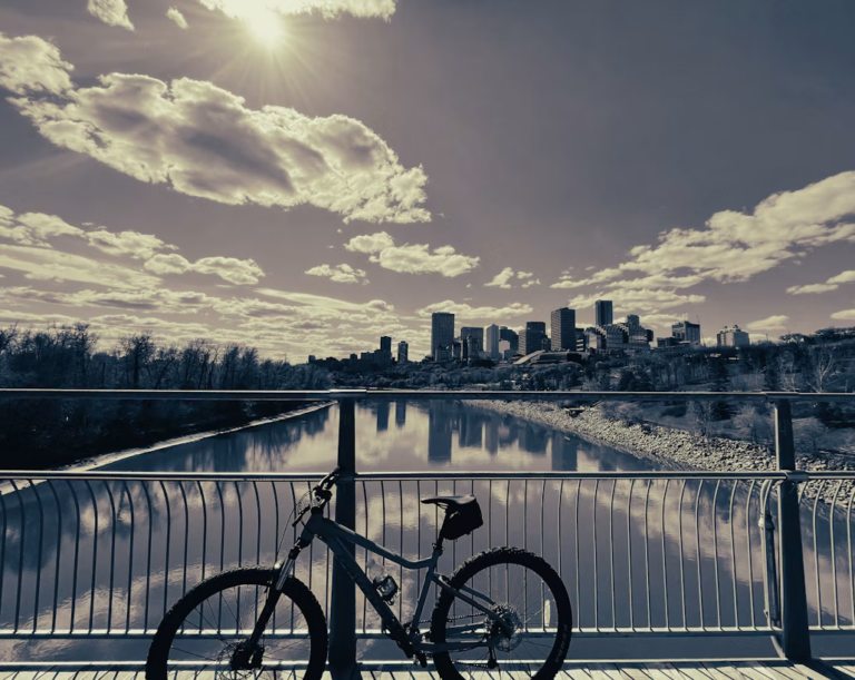 Cyclist riding a paved multi-use trail through Edmonton's North Saskatchewan River valley in summer