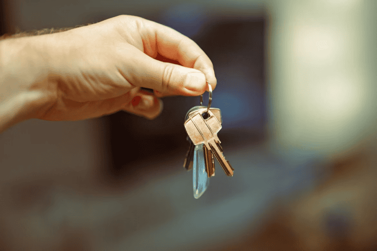 Edmonton landlord handing keys to a new tenant, illustrating the self manage vs property manager decision