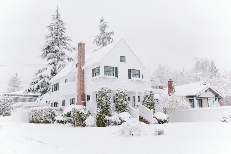 Snow-covered Edmonton house with a for sale sign at dusk, a guide to selling home in winter